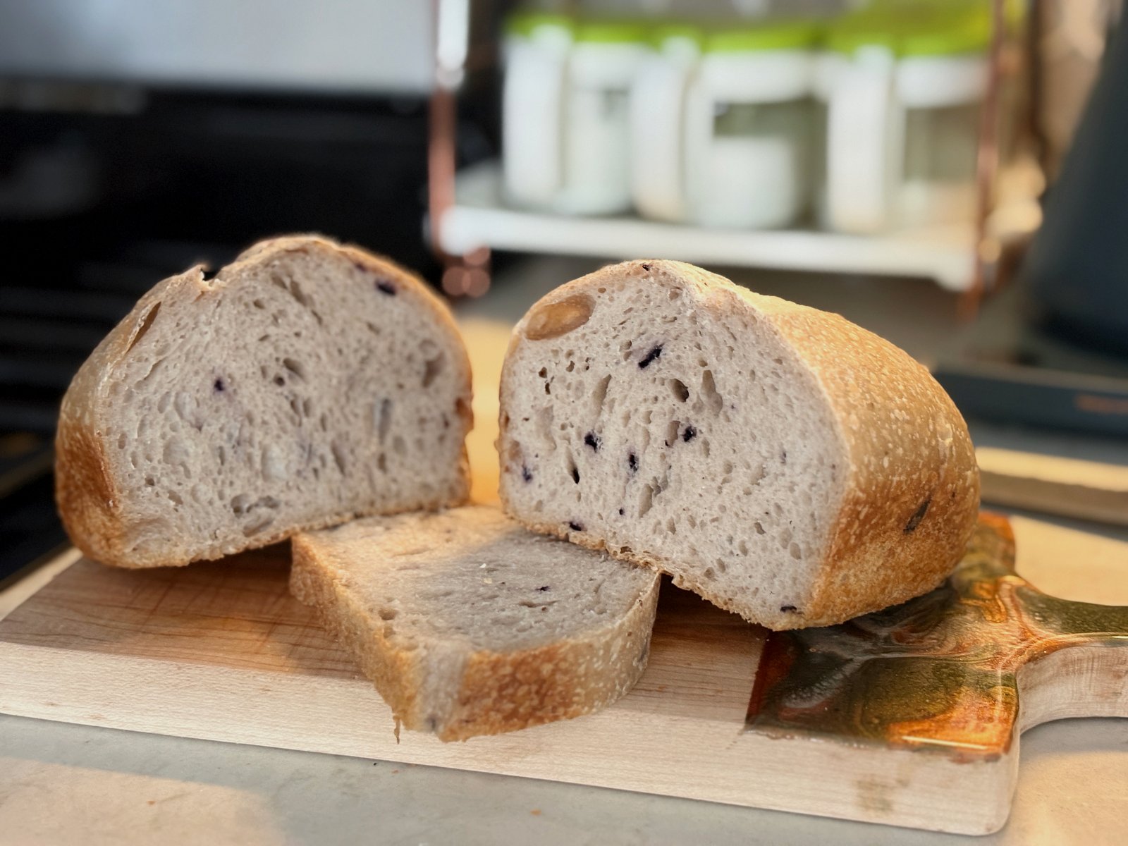 Sliced berry sandwich loaf with golden crust and berry-speckled crumb on a wooden cutting board